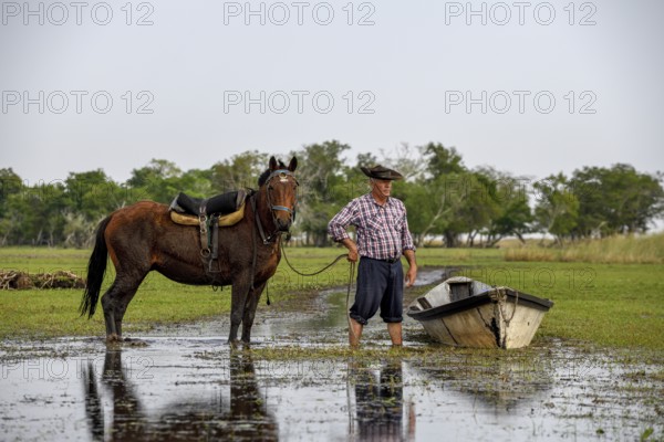 Gaucho with horse and boat at Puesto Mingo, Esteros del Iberá, near Concepción del Yaguareté Corá, Corrientes Province, Argentina, South America