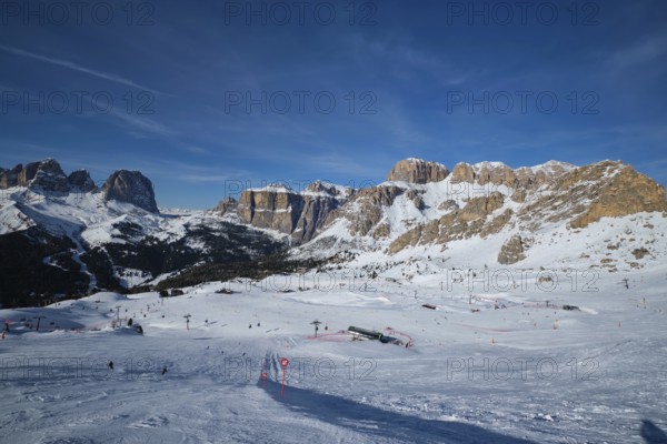 View of a ski resort piste with people skiing in Dolomites in Italy. Ski area Belvedere. Canazei, Italy, Europe