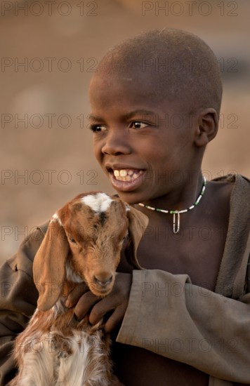 Himba boy with a goat, Ombombo, Kaokoland, Kunene, Namibia, Africa