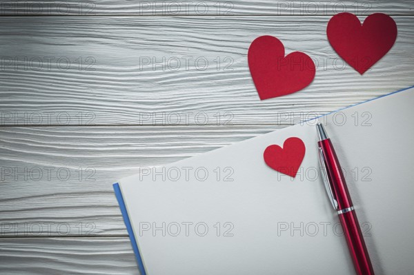 Red hearts ballpoint pen notebook on wooden board education concept