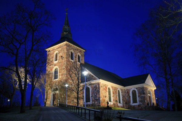 Illuminated Uskela Church, designed by Finnish architect C. L. Engel and built 1832, in winter nightfall. Salo, Finland. January 2020