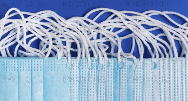 Close-up view of virus protection face mask with rubber ear straps on blue background as protection concept. Flat lay banner