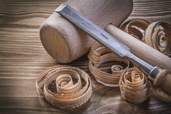 Wooden mallet flat chisels planning chips on vintage wood board construction concept