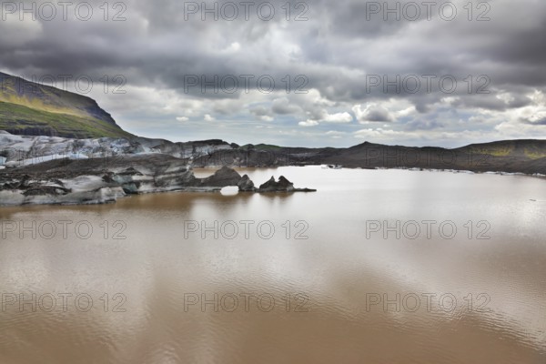 Skaftafell National Park. Ice covered with volcanic ash. Mirror Lake, formed as a result of thawing of a glacier Vatnajokull glacier spurs. Iceland in July