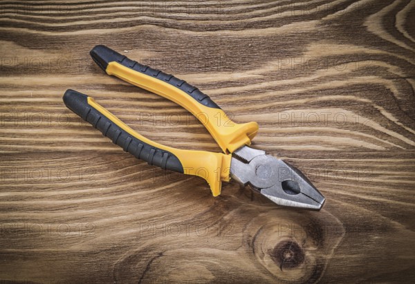 Gripping tongs on vintage wooden board construction concept