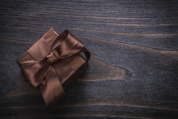 Boxed present with brown bows on vintage wood board