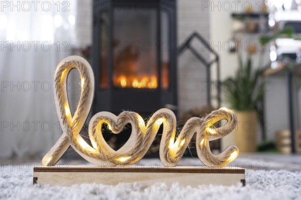 Valentine decor near fireplace stove with fire and firewood. Cozy home hearth in interior with potted plans, valentines day in family love nest