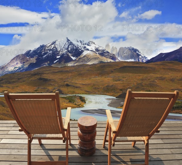 Pleasant holiday. Wooden chairs in the park Torres del Paine. Chile. On the horizon is visible snow-covered rocky mountain