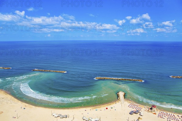 Magnificent sandy beach in Tel Aviv. Photo taken from the roof of a high-rise hotel. The blue waters of the Mediterranean attract tourists. Breakwaters reduce surf. Israel