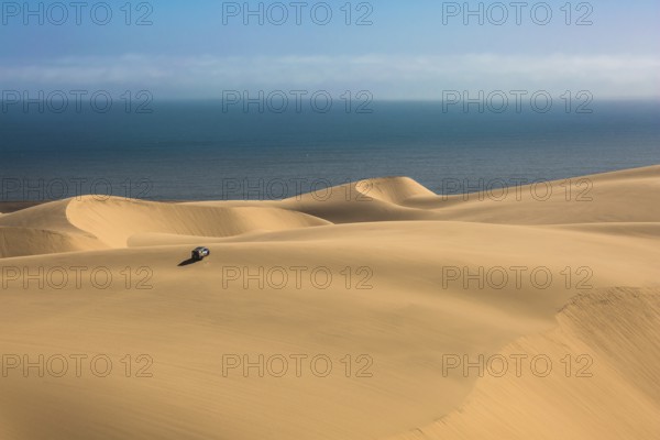 Gorgeous and dangerous jeep - safari through the huge sand dunes on the ocean coast. The concept of exotic and extreme tourism. Atlantic coast of Namibia, south of Africa