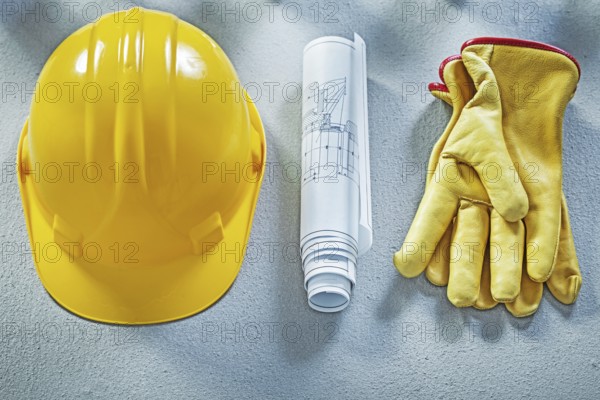 Building helmet protective gloves blueprints on concrete surface construction concept