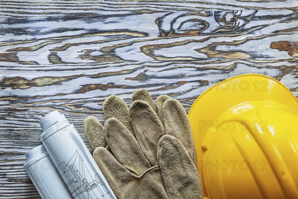 Pair of safety gloves construction plans hard hat on vintage wooden board