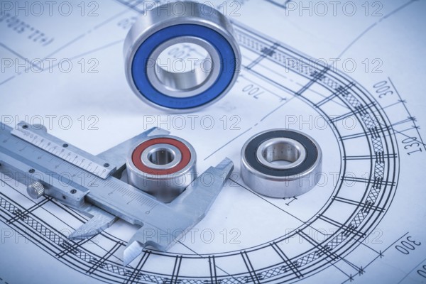 Metal roller bearings and trammel caliper on blueprint construction concept