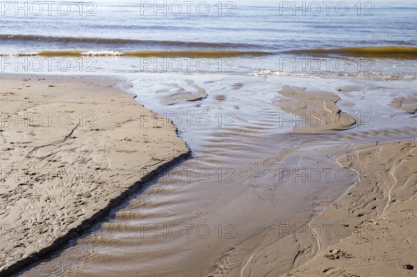 Gentle waves washing over the sandy beach creating small streams of water