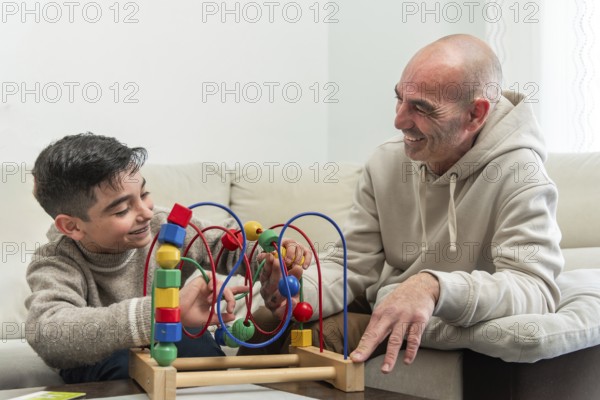 Grandfather and grandson enjoying quality time together, playing with a colorful wooden bead maze toy in living room