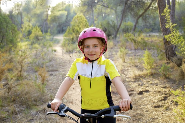 Kid girl biker in mountain bike MTB at mediterranean forest