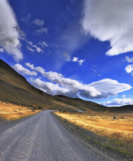 The dirt road in the Chile National Park Torres del Paine. Magic clouds incredible shapes formed by glaciers shining in the sun. Patagonia. Picture taken with a fisheye lens