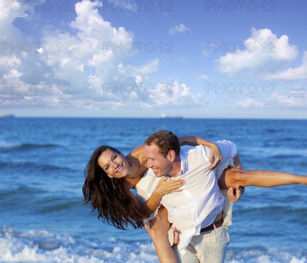 Couple in love piggyback playing in a beach at blue Mediterranean