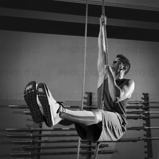 Rope Climb exercise man workout at gym climbing
