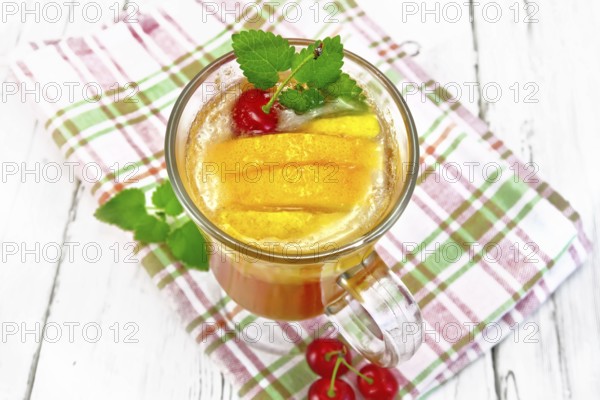 Lemonade in a wineglass with cherry, lemon and orange, mint on a napkin on a wooden plank background