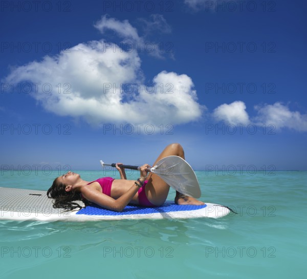 Girl relaxed lying on paddle surf board SUP relaxed in summer