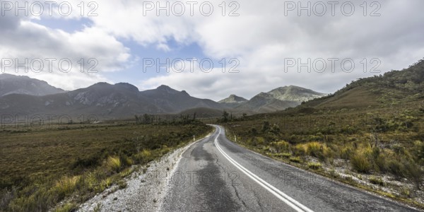 The picturesque Gordon River Rd at the Sentinel range of mountains near Bitumen Bones Sculpture on a cool wet summer's morning in Southwest National Park, Tasmania, Australia, Oceania