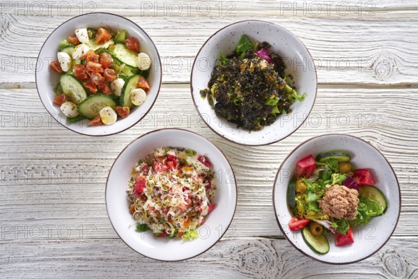 Four salad mix bowls healthy food on white wood table