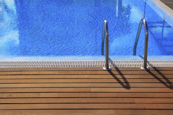 Blue swimming pool with teak wood flooring deck summer vacation concept