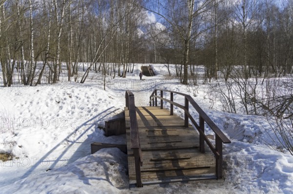 A bridge over a stream at the bottom of a small ravine. Teplostanovsky forest park, Moscow, Russia. Sunny day at the end of March