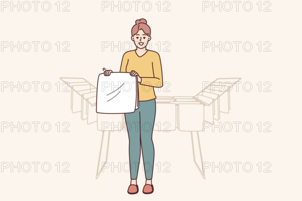 Woman housewife stands near dryer with clean towels doing household chores to create comfort in apartment. Housewife girl with washed item for advertising washing powder or aromatic laundry gel