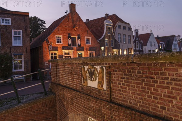 Brick houses and historic buildings illuminated in the evening twilight along a canal