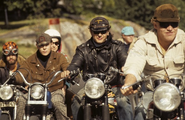 In the 1960s. Motorcyclists on the road together. Cool and trendy looking riding thir bikes. The law of wearing a safety helmet is not yet in force and at this time it was popular to wear caps. The jacket is typical 1960s with a wool collar. Sweden 1968. ref CV29