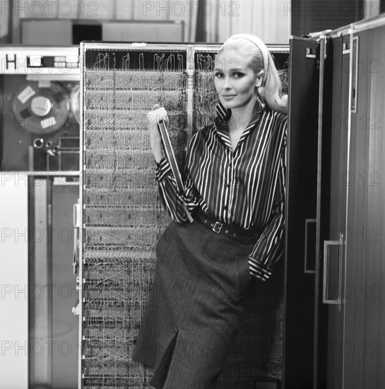 In the 1960s. Fashion model wearing the typical clothes of 1965. The photograph is taken in a 1960s mainframe computer room. Picture taken 1965. ref DV16