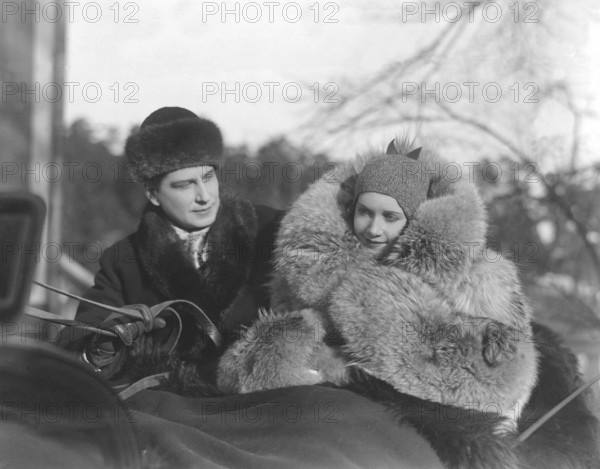 Fur coat in the 1930s. A young couple is sitting together in a horse drawn sledge. The woman is wearing a warm fur coat. Picture from the filming of the movie Charlotte Löwensköld 1930