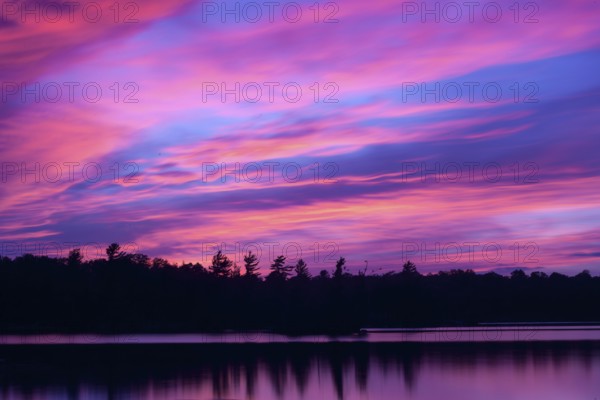 Vibrant colours start to fill the sky as dusk falls over the Kawartha cottage country region located northeast of Toronto in Ontario, Canada, North America