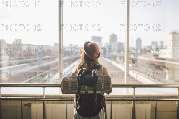 Traveler Rear view woman standing at the window in hall Train Station departure with backpack, Selective focus, Travel concept. transportation concept. Theme travel public transport