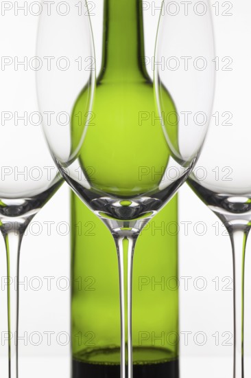 Three empty glasses of wine and green bottle on the white background
