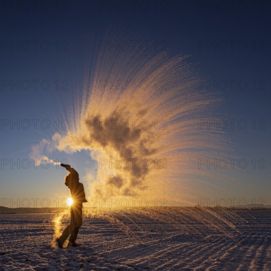Woman throws hot water into the air that freezes into ice crystals, Mpemba effect, Unterallgäu, Bavaria, Germany, Europe