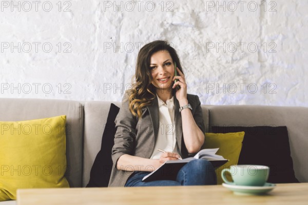 Businesswoman Using Phone Working On Laptop In Coffee Shop. woman calling with cell telephone, sitting alone in coffee shop during free time. Freelancer blogger. Work outside the office. Coworking