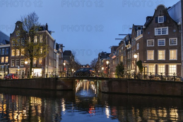Reflection of lights on a quiet canal under an illuminated bridge, Amsterdam, Netherlands