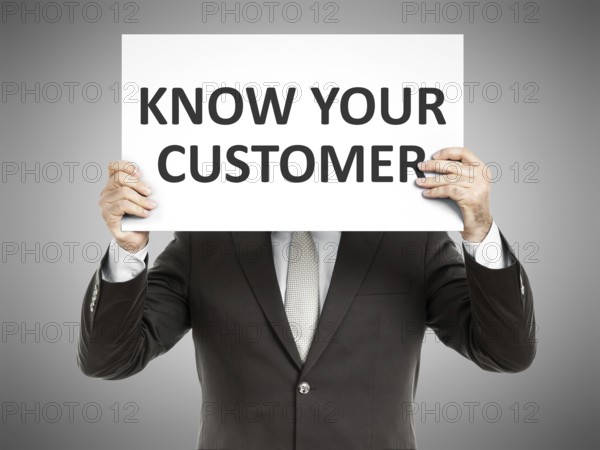 A business man holding a paper in front of his face with the text know your customer
