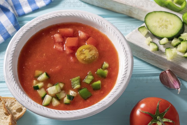 Gazpacho Andaluz is an Andalusian tomato cold soup from Spain with cucumber, garlic, pepper on light blue background
