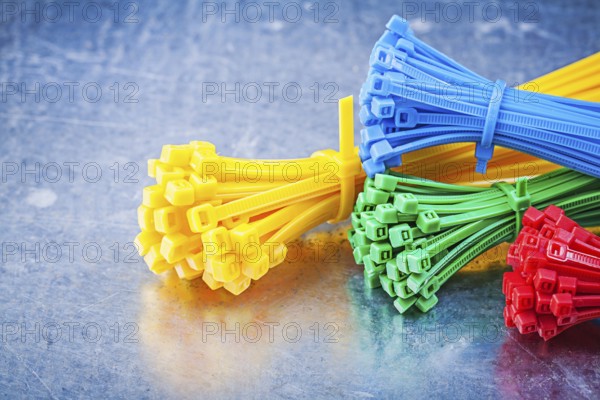 Multicolored plastic zip cable ties on metallic background construction concept