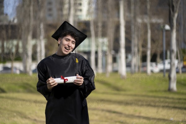 Young gay man recent graduated, dressed in cap and gown, showing off his degree celebrating