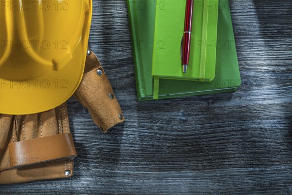 Notepads pen building helmet tool belt on wooden board