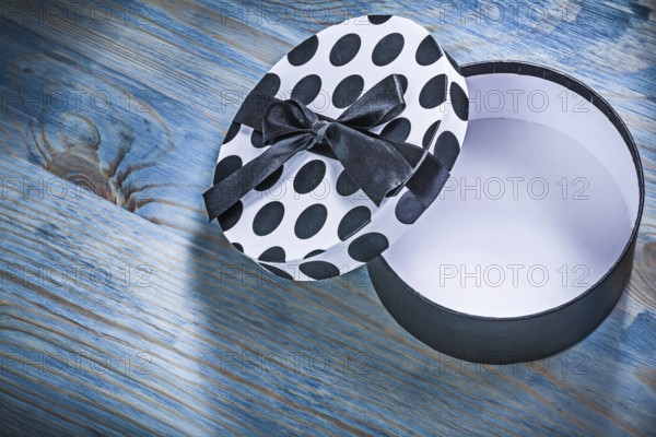 Round opened gift box with blue bow on wooden board holidays concept