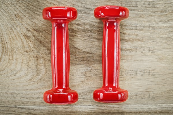 Red dumbbell weights on wooden board fitness concept