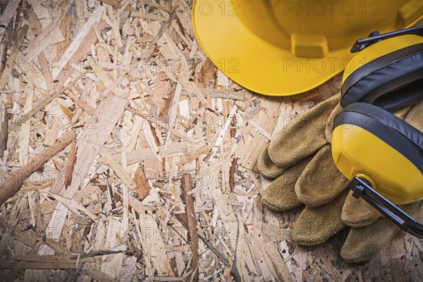 Safety leather gloves hard hat ear muffs on OSB