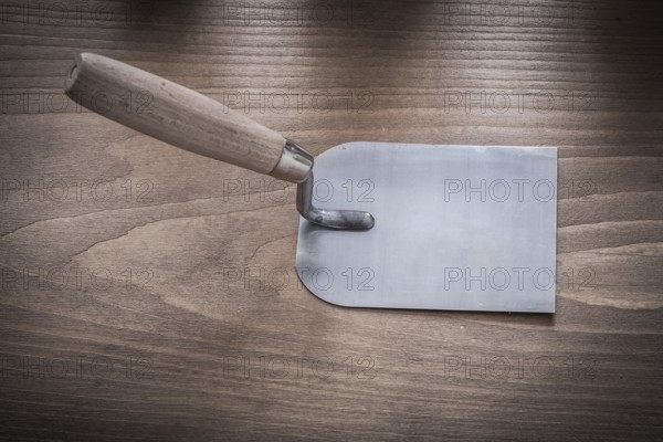 Metal bricklaying trowel on vintage wood board horizontal image