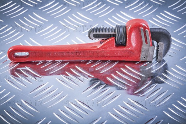 Monkey wrench on channeled metal background construction concept